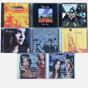 K&ouml;nnte beinhalten: Eine Sammlung von neun Compact Discs (CDs) mit verschiedenen K&uuml;nstlern, darunter Hanson, Paula Cole, The Verve, Norah Jones, No Doubt und mehr. Die CDs sind in drei Reihen mit jeweils drei CDs angeordnet, wobei die Titel und K&uuml;nstlernamen auf den Vorderseiten sichtbar sind.