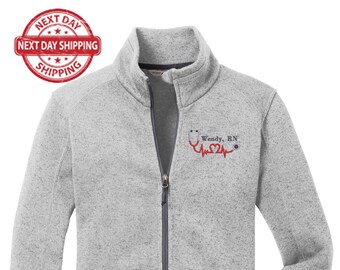 May include: A gray fleece zip-up jacket with a red embroidered stethoscope, heart, and the text "Wendy, RN".