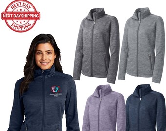 May include: A navy blue, heather grey, light purple, and dark blue women's fleece jacket with a zipper closure. The jacket has two zippered pockets on the front and a stand-up collar. The navy blue jacket has an embroidered design of two footprints with a heart and the text "Anna, BSN RN, NICU".