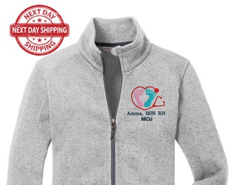 May include: A gray fleece zip-up jacket with a small embroidered logo on the left chest. The logo features a heart with two footprints inside and the text "Amma, BSN RN NICU".