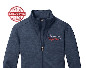 May include: A navy blue zip-up jacket with a red embroidered stethoscope and heartbeat graphic. The text "Wendy, RN" is embroidered below the graphic.