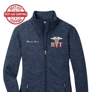 May include: A navy blue fleece jacket with a zipper closure. The jacket has a white embroidered logo with the text "RT" and a medical symbol. The text "Name here" is embroidered on the left side of the jacket.