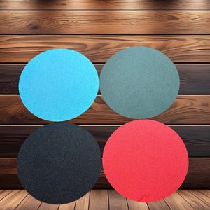 May include: Four circular objects in blue, green, black, and red. The objects are arranged in a square pattern against a wooden background. The circles appear to be made of a textured material.