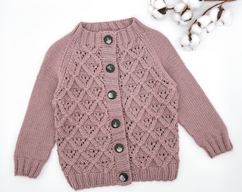 May include: A dusty rose knitted cardigan with a button-up front and a delicate openwork pattern.