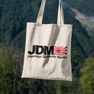 May include: A beige tote bag with black text that reads "JDM Japanese Domestic Market" and a red and white Japanese flag.