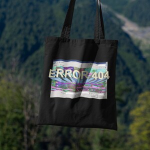 Può includere: Borsa tote nera con una grafica di uno schermo di computer blu e bianco con il testo "ERROR 404" in un font colorato e glitchato.