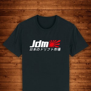 May include: A dark blue t-shirt with a white graphic of the text "Jdm" and a red rising sun symbol. The text below the graphic reads "日本のドリフト市場".