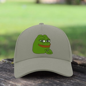 Può includere: Cappellino da baseball grigio con un personaggio di rana verde dei cartoni animati. La rana ha un'espressione pensierosa e una bocca rossa. Il cappellino è realizzato in materiale morbido e ha una visiera curva.