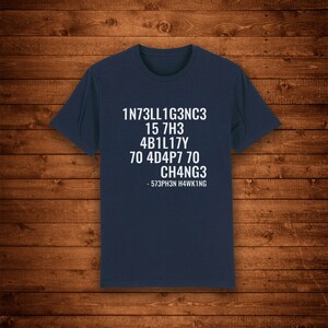 May include: A navy blue t-shirt with white text that reads "1N73LL1G3NC3 15 7H3 4B1L17Y 70 4D4P7 70 CH4NG3 - 573PH3N H4WK1NG"