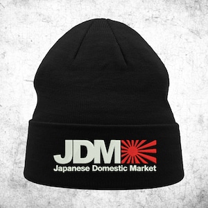 May include: Black beanie with a white "JDM" logo and a red rising sun graphic. The text below the logo reads "Japanese Domestic Market."