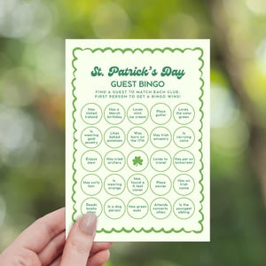 Op de afbeelding: Een St. Patrick's Day Gast Bingo kaart met een groene rand en tekst. De kaart bevat verschillende prompts zoals "Heeft Ierland bezocht" en "Houdt van muntsmaak ijs". De kaart wordt door een persoon vastgehouden.