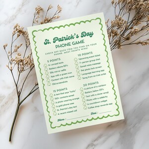 Könnte beinhalten: Ein druckbares St. Patrick's Day-Handyspiel mit einem grünen Kleeblatt-Rand. Das Spiel fordert die Spieler auf, jedes Element abzuhaken, das sie auf ihrem Handy finden, wobei Punkte für verschiedene Elemente vergeben werden. Das Spiel umfasst Kategorien für 5 Punkte, 10 Punkte, 15 Punkte und 20 Punkte.