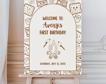 Puede incluir: Un letrero crema sobre un caballete con ilustraciones y texto marrón. El letrero dice "Welcome to Avery's First Birthday" con un gráfico de fogata. El borde presenta dibujos de s'mores y malvaviscos. La fecha es sábado 12 de julio de 20XX.