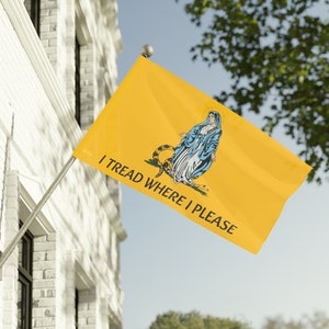 May include: A yellow flag with a blue and white image of a woman standing on a snake with the text "I Tread Where I Please".