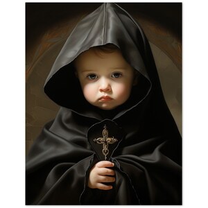 May include: A portrait of a baby wearing a black hooded robe, holding a gold cross. The baby has a serious expression, with the dark hood framing the face. The background has a soft, warm tone.