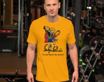 May include: A yellow short-sleeved t-shirt featuring a graphic of a winged angel standing on a snake. The text "I tread where He pleases" is printed below the graphic.