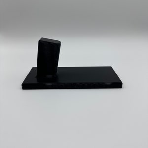 May include: A black plastic stand with a raised platform for displaying a small object.