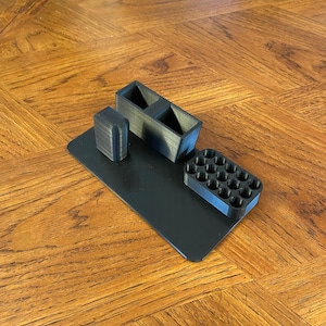 Puede incluir: Un organizador de escritorio de impresión 3D negro con compartimentos para bolígrafos, lápices y otros artículos de oficina.