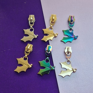 May include: Six gold and iridescent zipper pulls shaped like holly leaves with a small Mickey Mouse head charm.