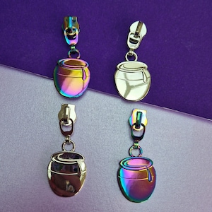 May include: Four zipper pulls with a pot design. Two are silver and two are iridescent.