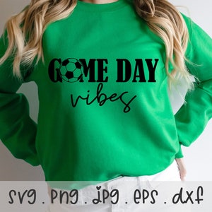 May include: Green sweatshirt with black text that reads "Game Day Vibes" and a black and white soccer ball graphic.