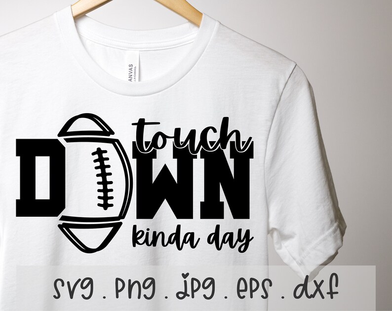 Puede incluir: Una camiseta blanca con un dise&ntilde;o gr&aacute;fico negro que dice "Touchdown kinda day" con un gr&aacute;fico de f&uacute;tbol. El gr&aacute;fico est&aacute; en blanco y negro.