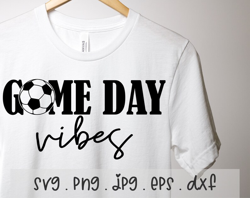 May include: White t-shirt with black text that reads "Game Day Vibes" and a black and white soccer ball graphic. The text "svg. png. jpg. eps. dxf" is printed below the graphic.