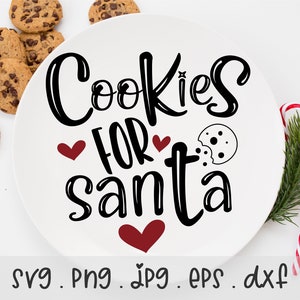 以下が含まれることがあります： 白いプレートに黒い筆記体で「Cookies for Santa」と書かれています。赤いハートが2つと、かじられたクッキーのイラストがあります。プレートはチョコレートチップクッキーとキャンディーケーンで囲まれています。