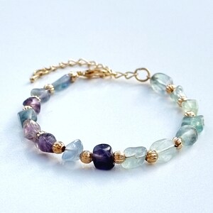 May include: A gold chain bracelet with a variety of light blue, green, and purple gemstone beads.