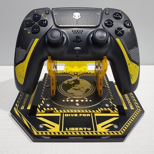 May include: A black and yellow PlayStation 5 controller on a black and yellow stand with the text "Dive for Liberty" and a globe graphic.