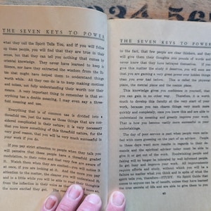 May include: An open book with two pages of black printed text on off-white paper. The header on both pages reads THE SEVEN KEYS TO POWER. The text discusses spiritual knowledge, mental planes, and the importance of study for personal success.