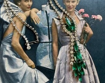 May include: A vintage rhinestone necklace with a long, dangling emerald green crystal pendant. The necklace is double-stranded and features a silver clasp.