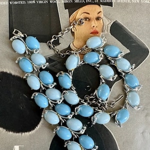 K&ouml;nnte beinhalten: Ein Vintage-Set aus Halskette und Armband in Silber mit hellblauen und dunkelblauen ovalen Glassteinen. Halskette und Armband sind beide aus Metall und haben ein zartes Design.