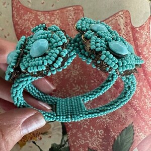 May include: A turquoise beaded bracelet with large turquoise cabochon stones. The bracelet is made of small, round beads and has a metal clasp.