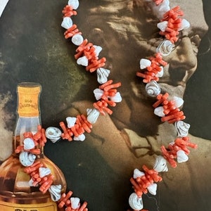 May include: A coral and shell necklace with a gold clasp. The necklace is made of small, red coral branches and white shell beads.