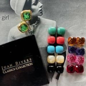 May include: A collection of Joan Rivers Classics Collection earrings. The earrings are square-shaped with gold-tone metal and colorful, faceted stones. The colors include green, red, blue, white, black, and various shades of pink and orange. A black box with gold lettering is also present.