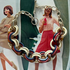 May include: A chunky chain necklace featuring interlocking circular links in cream, navy blue, and tortoiseshell brown resin, connected by polished silver-tone metal links and finished with a silver-tone toggle clasp closure.