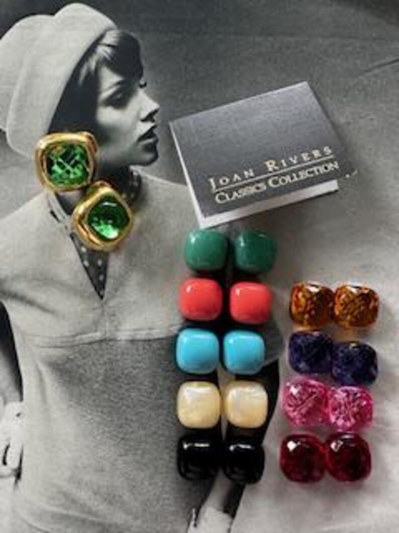 May include: A collection of vintage Joan Rivers Classics Collection earrings in various colors. The earrings are square or rectangular, with gold-tone metal settings. The image includes a pair of green gemstone earrings and a book with the text "Joan Rivers Classics Collection."