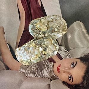 May include: A pair of gold and white resin bangle bracelets with a mosaic design. The bracelets are made of small pieces of resin and have a pearlescent finish.