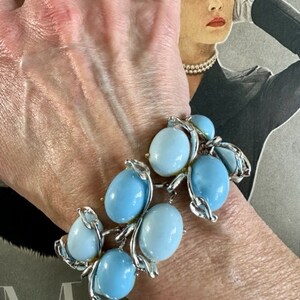K&ouml;nnte beinhalten: Ein silbernes Armband mit blauen und wei&szlig;en Glasperlen. Das Armband befindet sich am Handgelenk einer Person.