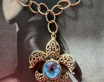 Collar de los años 60 con flor de lis heráldica, colgante de cristal azul metalizado y filigrana dorada, joyería medieval vintage de mediados de siglo.