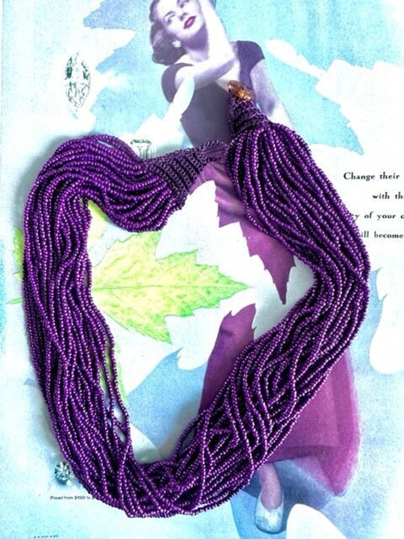 May include: A long purple beaded necklace with a tassel at the end. The necklace is made of small, round beads and is very long, reaching almost to the floor.