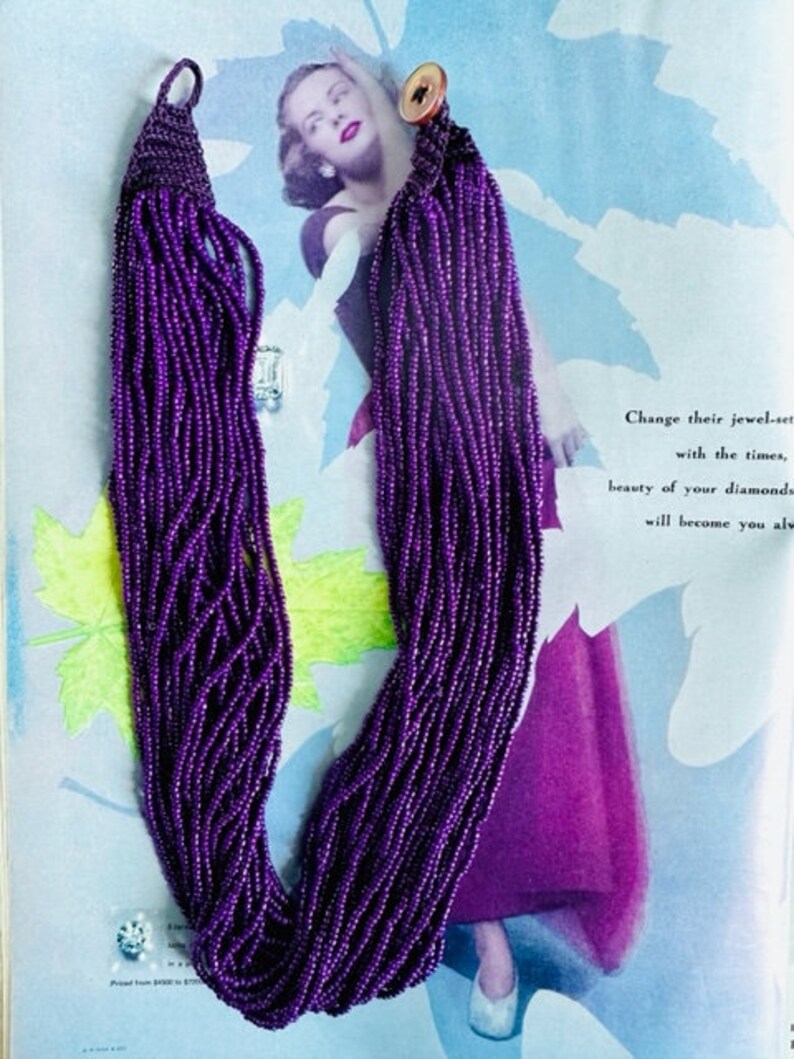 May include: A long purple beaded necklace with a gold button clasp. The necklace is made of many strands of small beads.