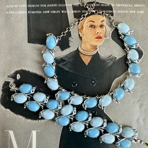 K&ouml;nnte beinhalten: Ein Set aus zwei blauen und silberfarbenen Halsketten mit ovalen Steinen. Die Halsketten liegen auf einem Magazin mit dem Text "TEXTURE IS THE NEWS... GROSGRANA IS THE TEXTURE" und "Miron THE BEST WOOL YOU CAN PUT ON YOUR BACK".