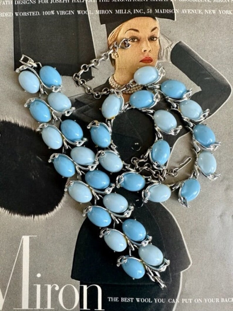 K&ouml;nnte beinhalten: Ein Vintage-Set aus Halskette und Armband in Silber mit hellblauen und dunkelblauen ovalen Glassteinen. Halskette und Armband sind beide aus Metall und haben ein zartes Design.