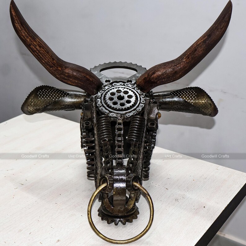 May include: A metal bull sculpture made from recycled materials. The sculpture features a detailed design with gears, chains, and springs. The horns are made of wood and the nose ring is made of brass.
