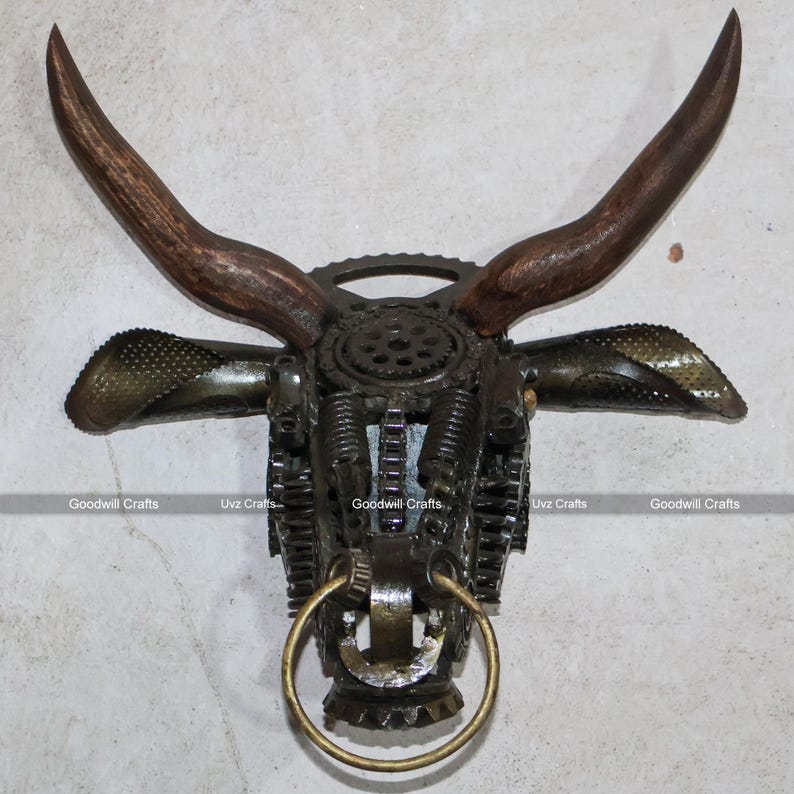 May include: A metal bull head sculpture made from recycled gears and other metal parts. The horns are made of wood and the nose ring is made of brass.