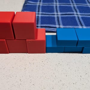 May include: A stack of red blocks and a row of blue blocks. The red blocks are arranged in a pyramid shape, while the blue blocks are arranged in a straight line.