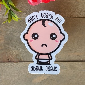 Puede incluir: Pegatina blanca con un bebé de dibujos animados con una expresión triste. La pegatina dice "no me enseñes sobre Jesús".