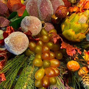 Puede incluir: Un arreglo con tem&aacute;tica oto&ntilde;al con una calabaza grande y escarchada, orbes azucarados y un racimo de uvas verdes y &aacute;mbar. El arreglo incluye agujas de pino, hojas de oto&ntilde;o y peque&ntilde;as calabazas en tonos naranja, rojo y verde.